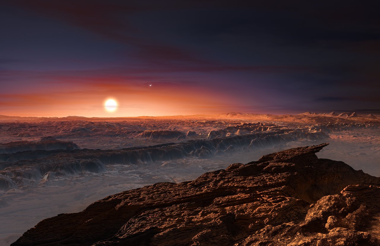 Wizja artystyczna prezentuje widok powierzchni planety Proxima b, okrążającej czerwonego karła Proxima Centauri, najbliższą gwiazdę względem Układu Słonecznego. Gwiazda podwójna Alfa Centauri AB także jest widoczna na obrazku, na prawo, w górę od Proximy. Proxima b jest nieco bardziej masywna niż Ziemia i krąży w ekosferze (tzw. strefie życia) wokół Proximy Centauri, gdzie panuje temperatura odpowiednia dla występowania wody w staniej ciekłym na powierzchni planety.