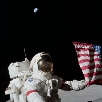 Gene Cernan pozuje do zdjęcia z flagą Stanów Zjednoczonych.