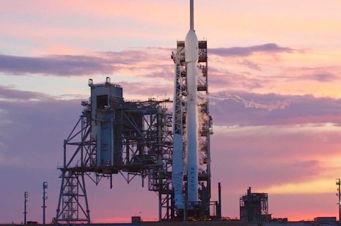 Flagowy statek SpaceX na tle podświetlanych przez zachodzące Słońce chmur, przez które początek poniedziałkowego odliczania został przełożony o prawie godzinę, 